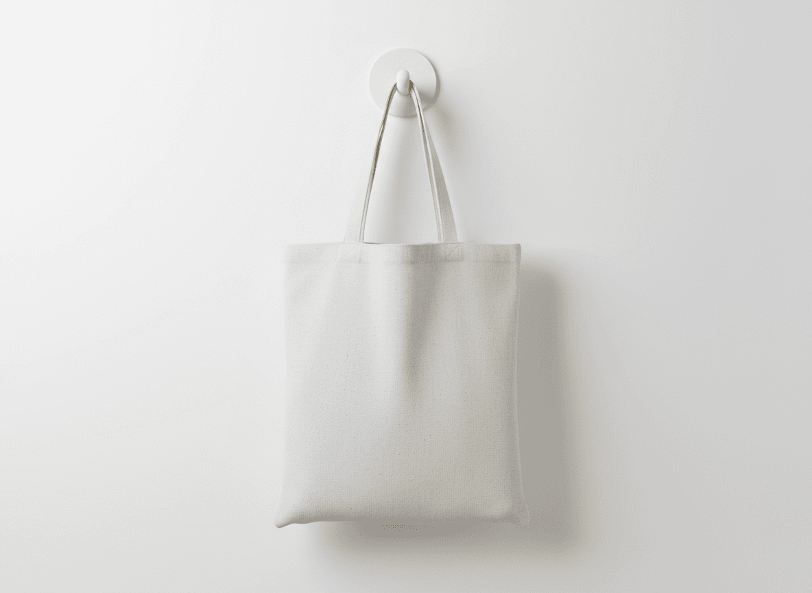 흰색 벽걸이에 걸려 있는 캔버스 에코백 목업 이미지.