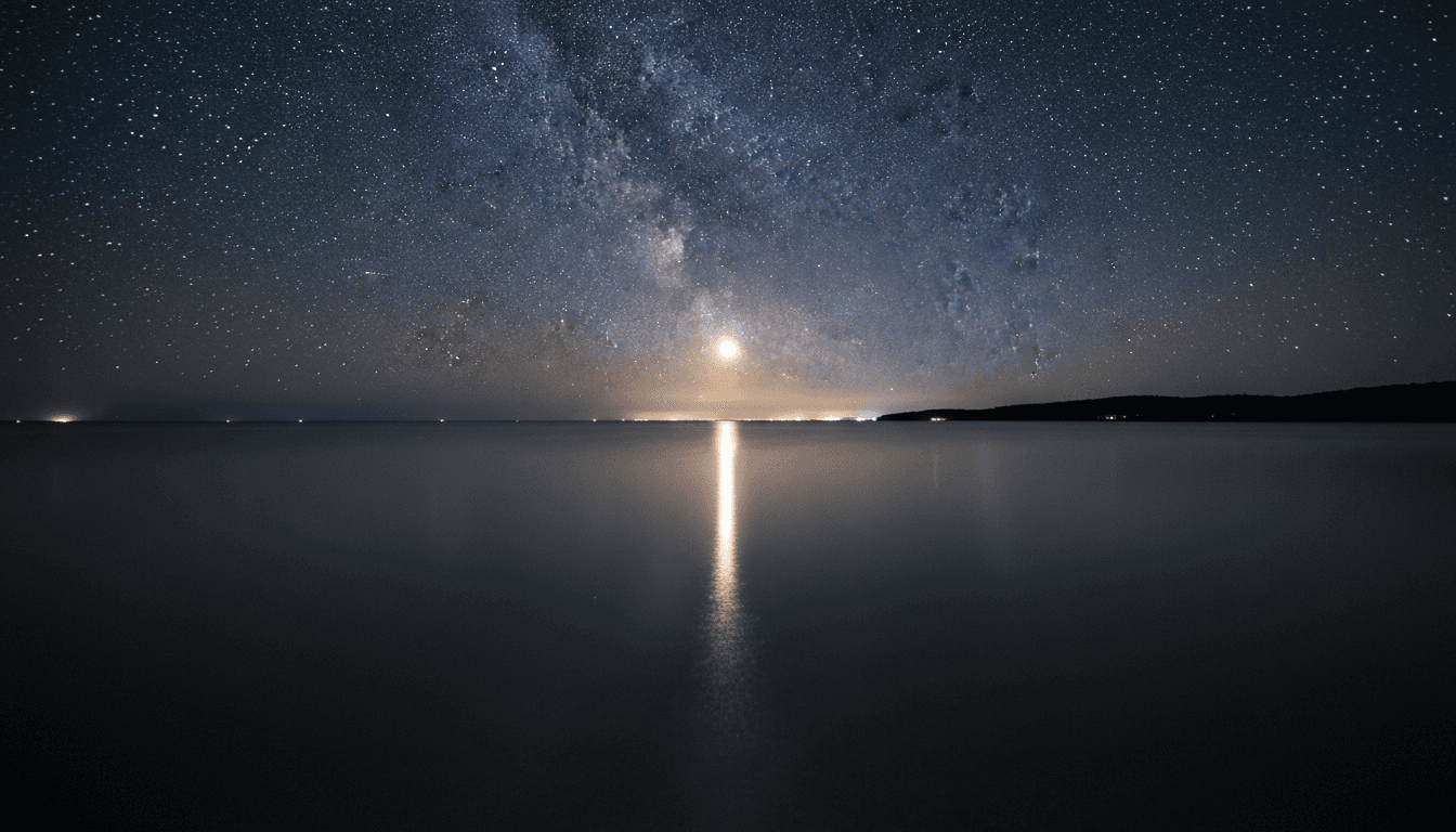 잔잔한 바다 표면에 달빛과 고요한 밤하늘이 비치는 모습.