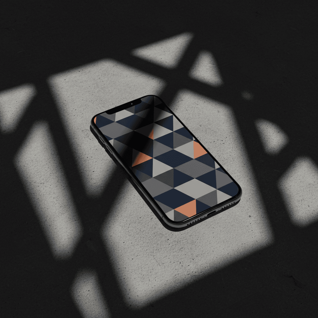 기하학적 배경화면을 가진 아이폰 목업, 콘크리트 표면에 드리워진 극적인 그림자.