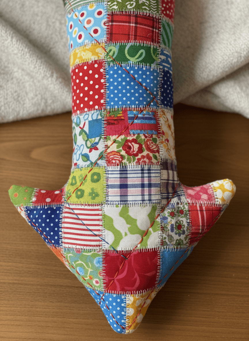 다채로운 패치워크 천으로 만든 엉뚱한 화살표가 아래를 가리키고 있음.