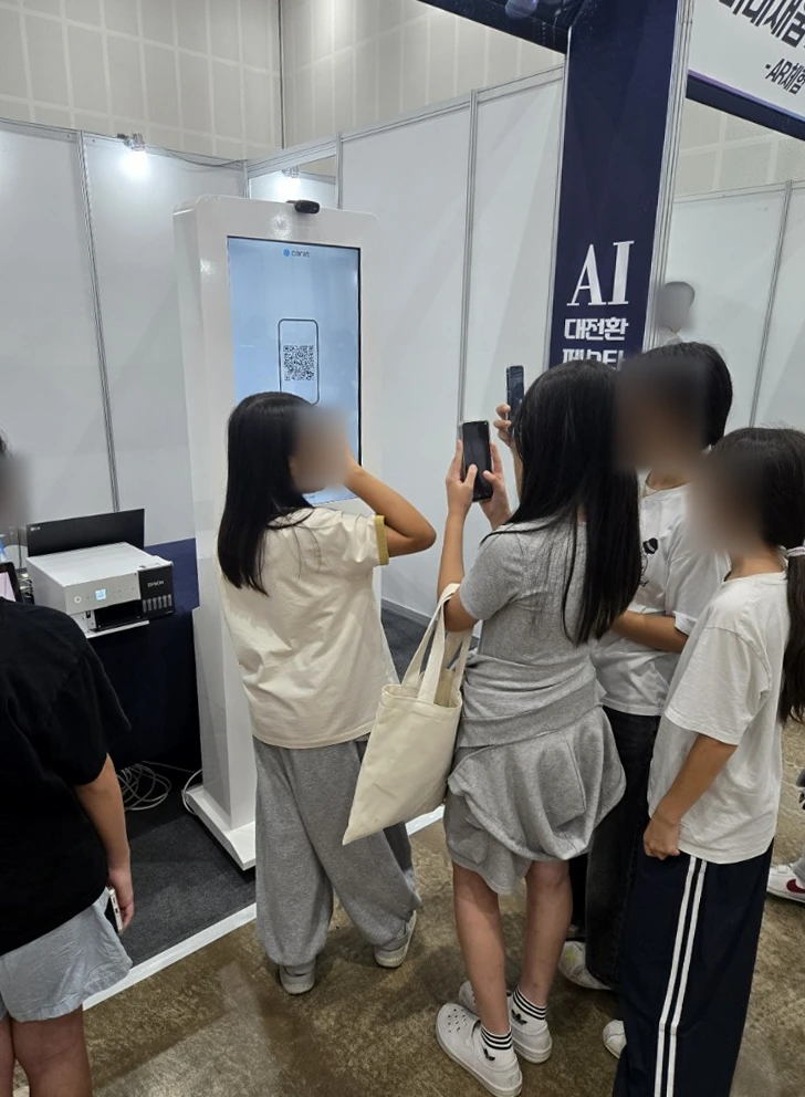 키오스크에 표시된 QR을 휴대폰으로 확인하는 참가자들