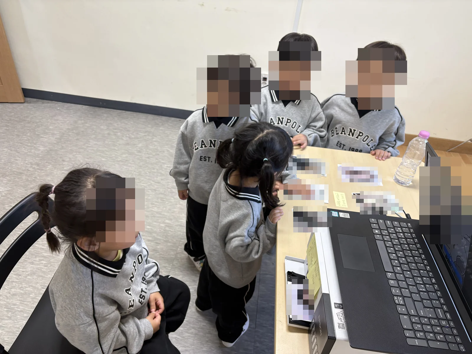테이블 위 인화 결과물을 살펴보는 어린이들